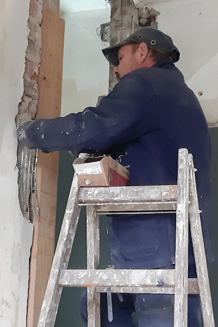 Der Maler schraubt Streckmetall an die Wand bevor er putzt.