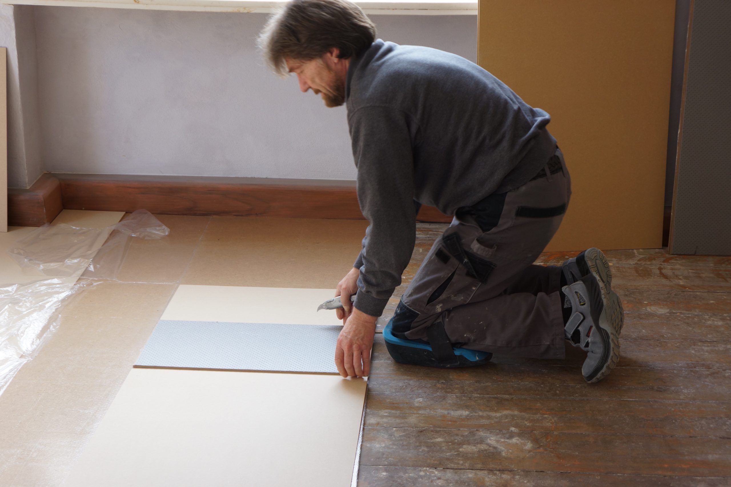 Der Handwerker hat den Raum vorher vermessen und schneidet die Platten zu, damit sie passgenau den gesamten Boden abdecken.