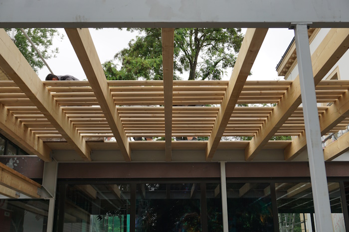 Die Dachkonstruktion aus Metallträgern und -stützen sowie Holzbalken wird mit Rauhspundbrettern geschlossen.